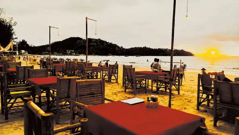 Tables on the sand at sunset over the bay