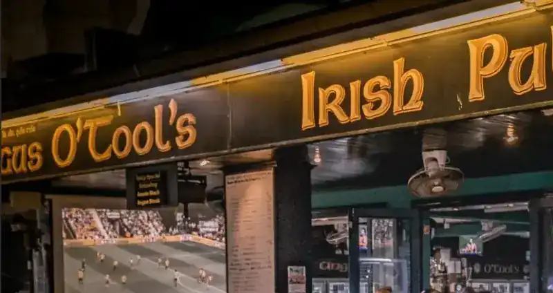 The gold-lettered Irish Pub sign over the bar, with a match on the big screen below