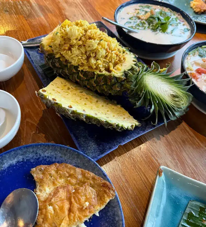 Pineapple fried rice served in a halved pineapple, with a coconut soup and an omelette