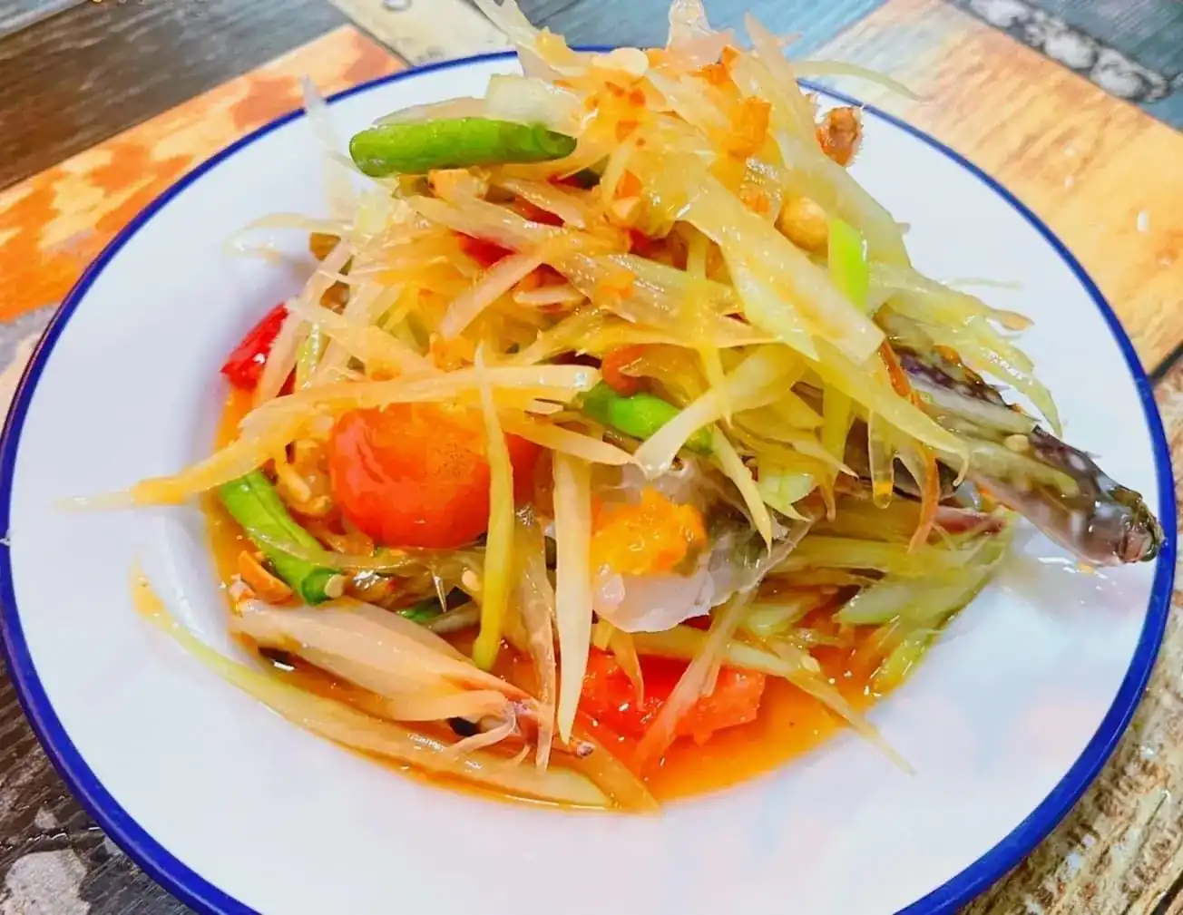 Som tam with crab, long beans and tomato on a blue-rimmed enamel plate