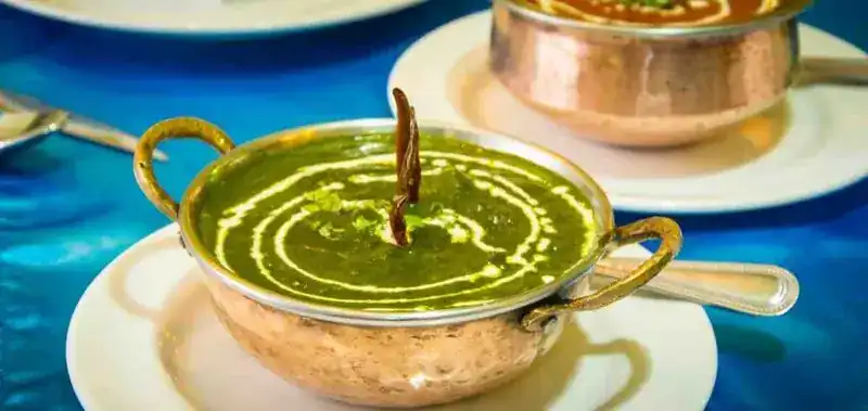 Saag paneer in a copper karahi with a cream swirl
