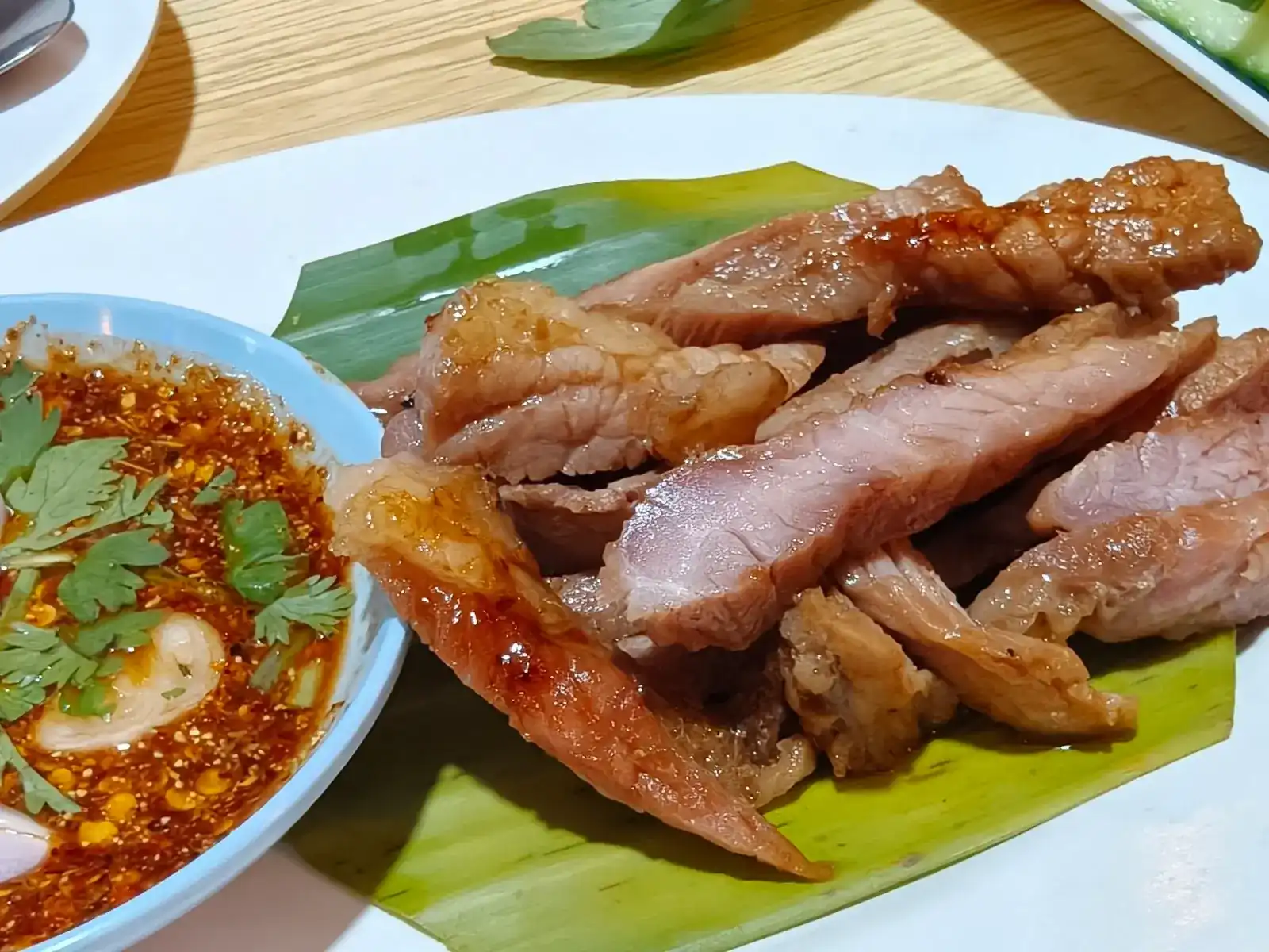 Grilled pork on a banana leaf with a chilli dipping sauce