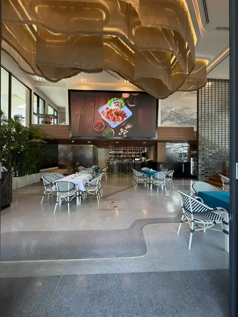 The dining room inside, with a rippling gold ceiling, white and teal tables and the bar at the back