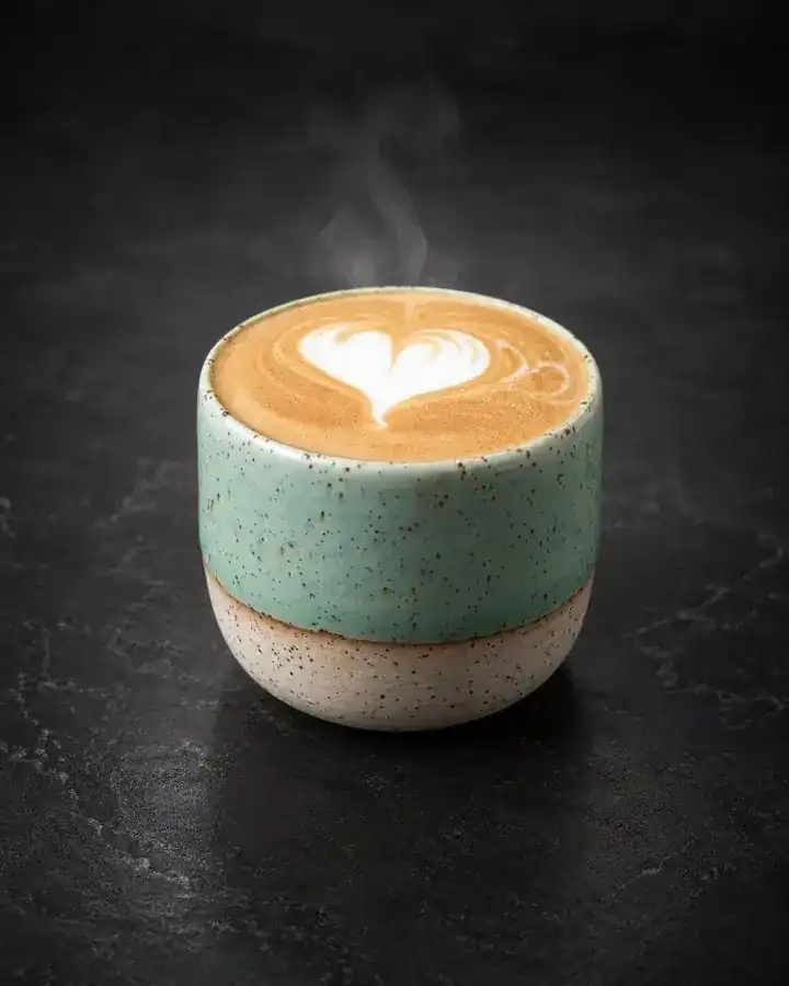 Hot cappuccino in a speckled green ceramic cup