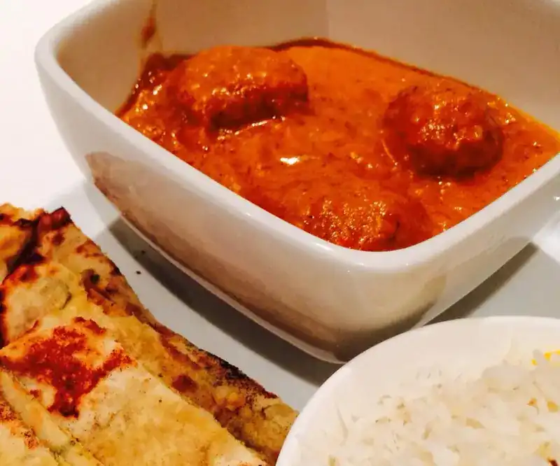 Koftas in an orange gravy, with naan and rice