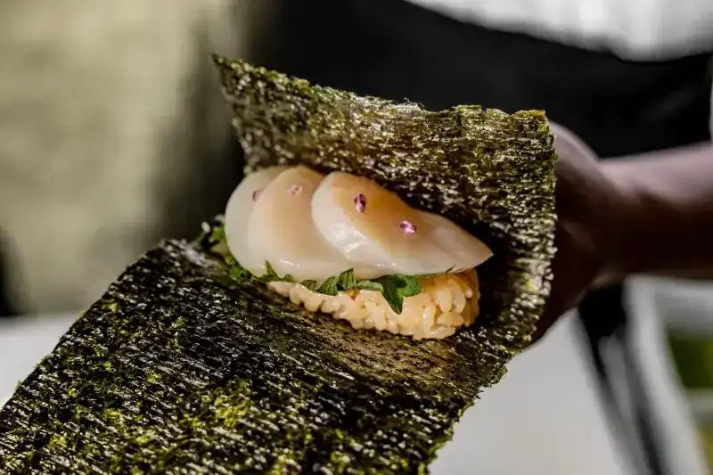 Scallop slices with shiso flower on rice in a sheet of nori