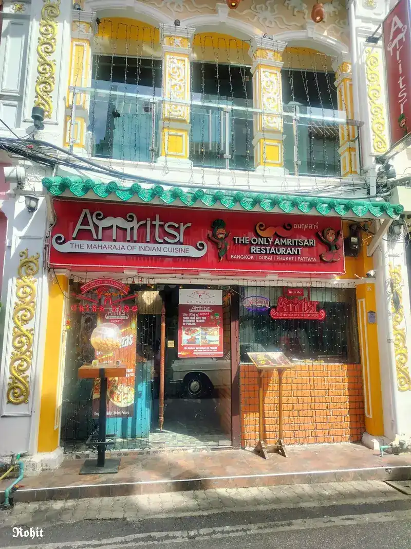 The Amritsr shopfront: a red sign under green roof tiles on a yellow and white shophouse