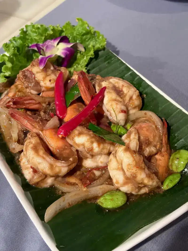 Prawns stir-fried with red chilli, onion and sator beans on a banana leaf