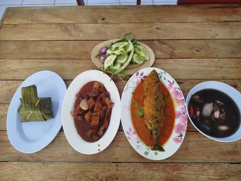 Hor mok in banana leaf, a pork dish, fish in curry and fresh vegetables on a wooden table