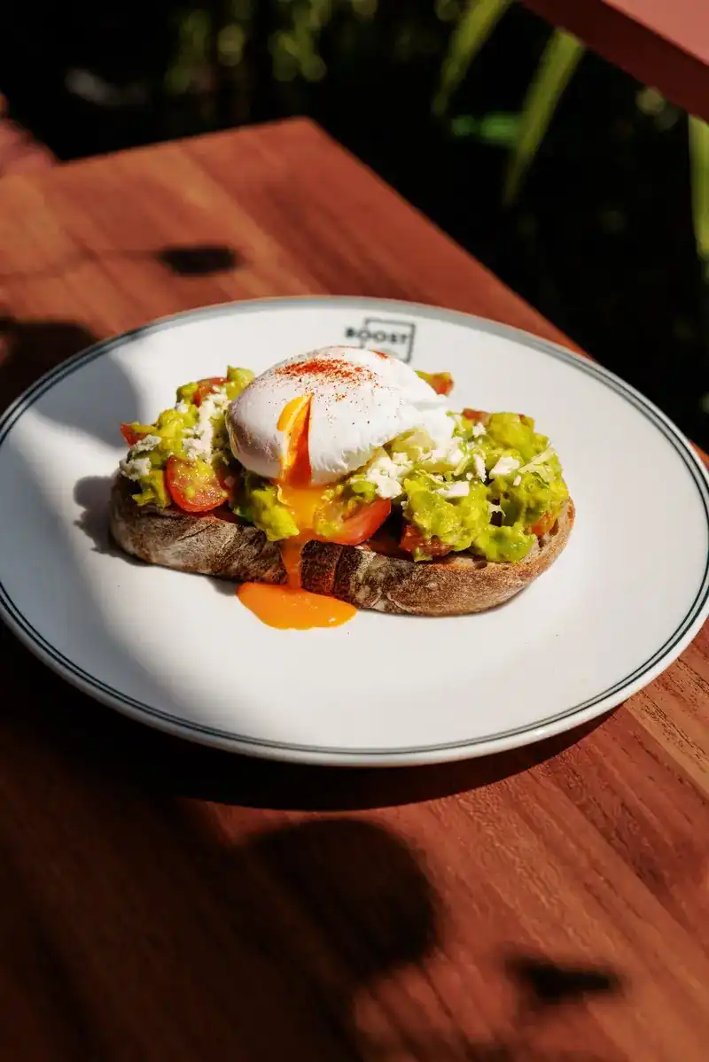 A poached egg, yolk running, on smashed avocado sourdough