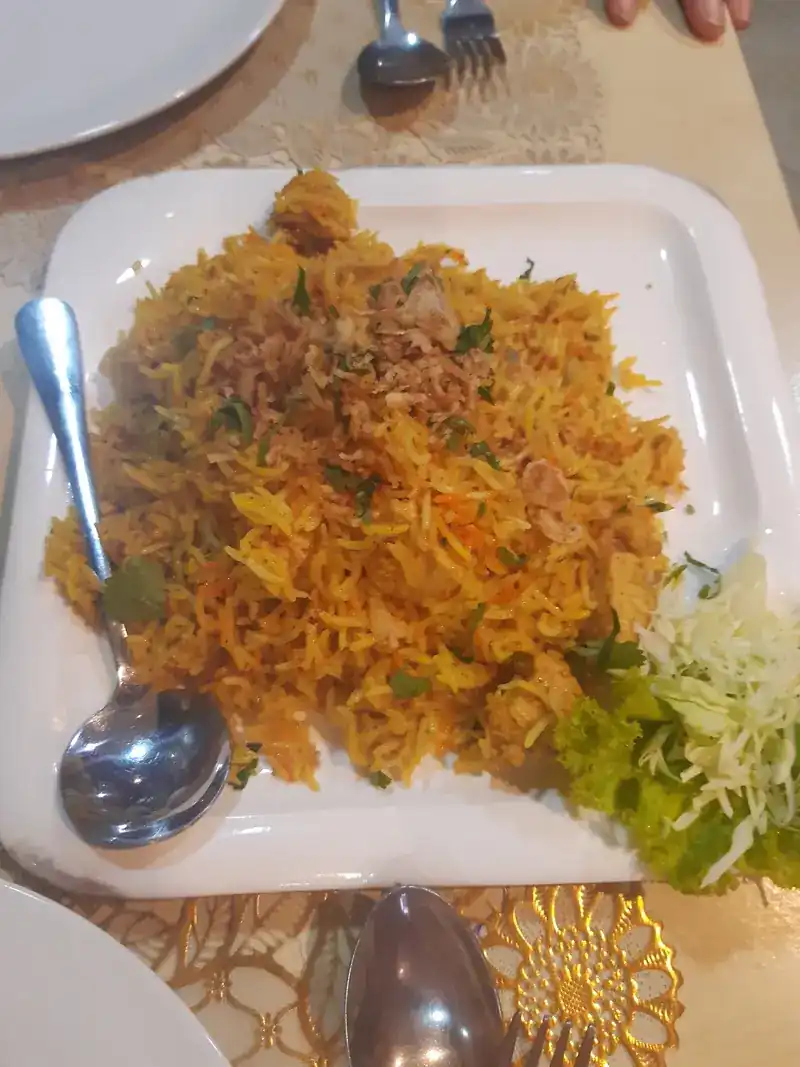 A plate of biryani with fried onion on top