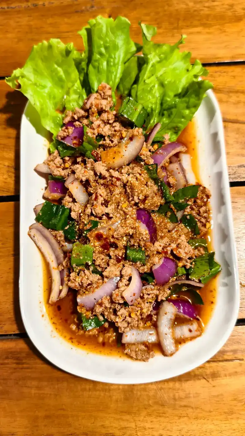 Larb with red onion and herbs on lettuce