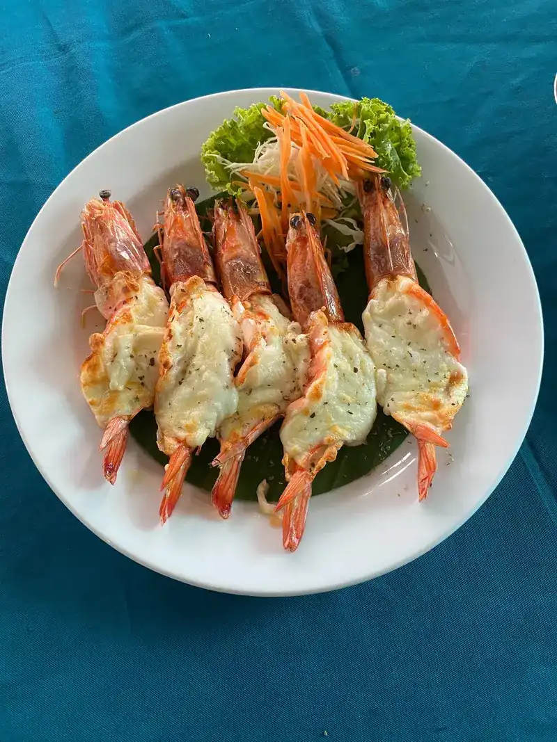Six large prawns, split and topped, on a white plate with carrot and lettuce