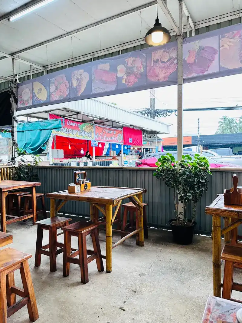 Wooden tables along the open side of the restaurant, facing the road