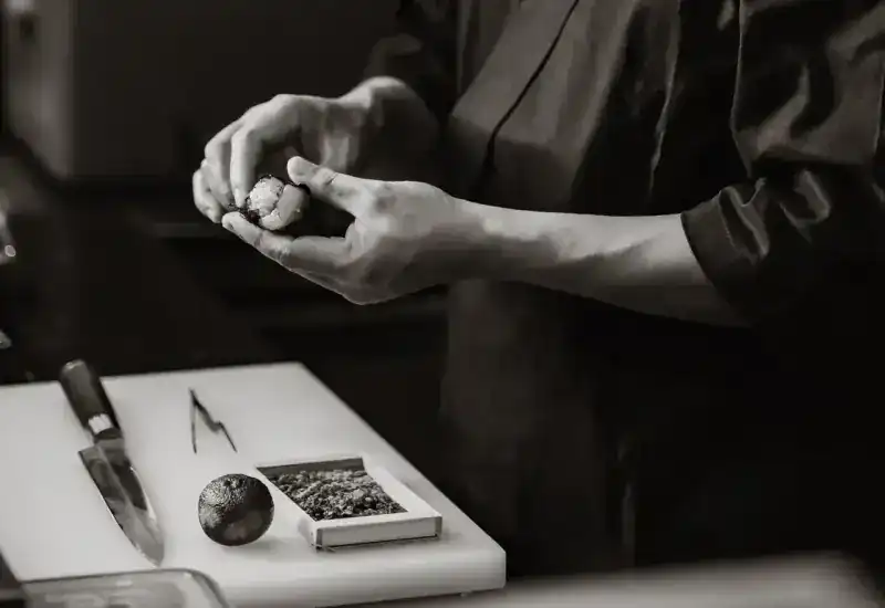 A chef's hands shaping rice beside a knife and a sudachi