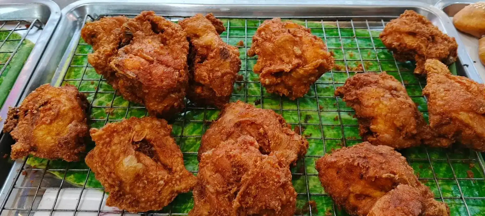 Fried chicken on a wire rack over banana leaf