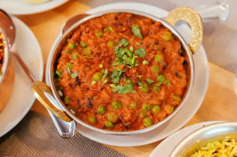 Curry with green peas and coriander in a copper-handled bowl