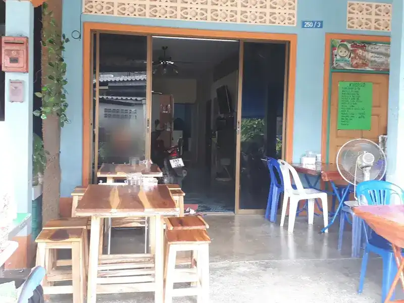 The shop front at 250/3 with wooden tables, blue chairs and orange door frames