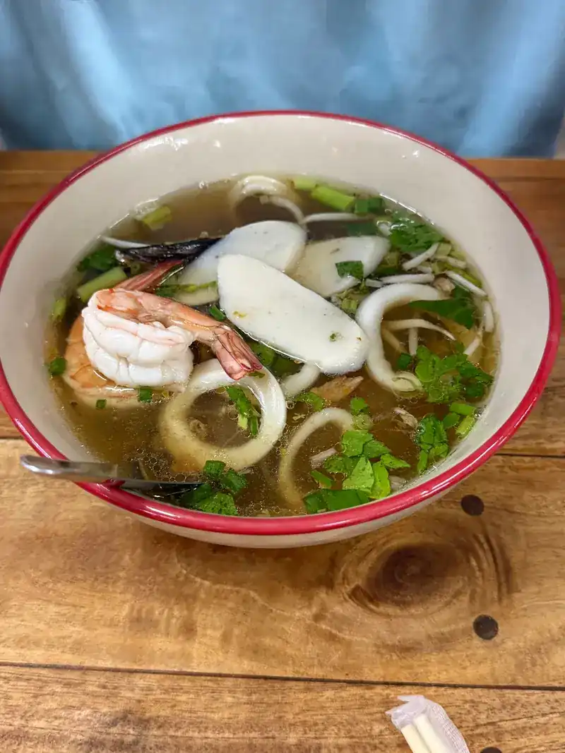 Seafood noodle soup with prawns and squid in a red-rimmed bowl / ก๋วยเตี๋ยวทะเล ใส่กุ้งและปลาหมึก ในชามขอบแดง