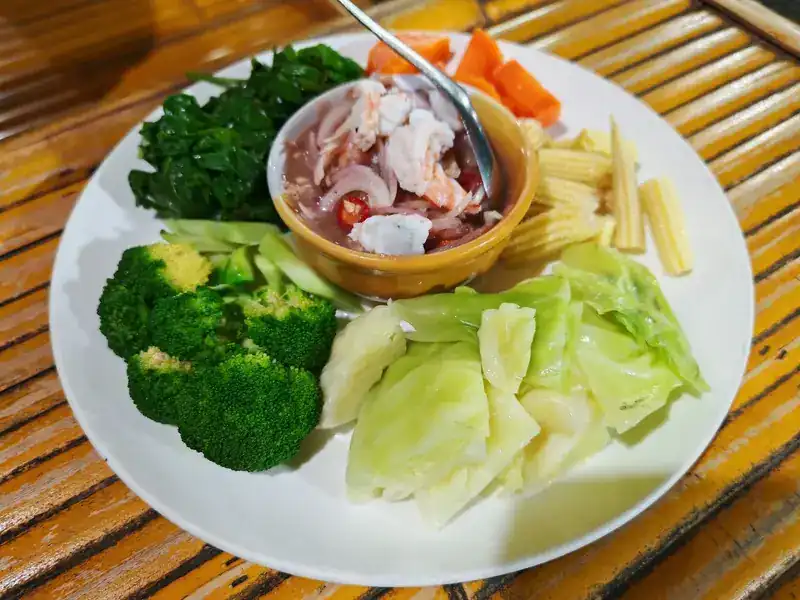 A prawn chilli dip in a small bowl, with blanched broccoli, cabbage, baby corn, carrot and greens