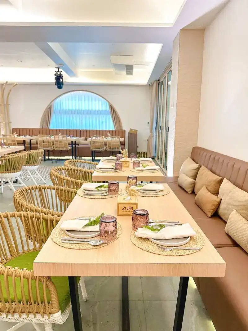 Banquette seating with cushions along a long table, an arched window at the end of the room