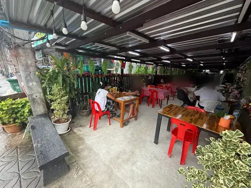 The open-air dining room under a tin roof, with red chairs and red-and-white checked tablecloths