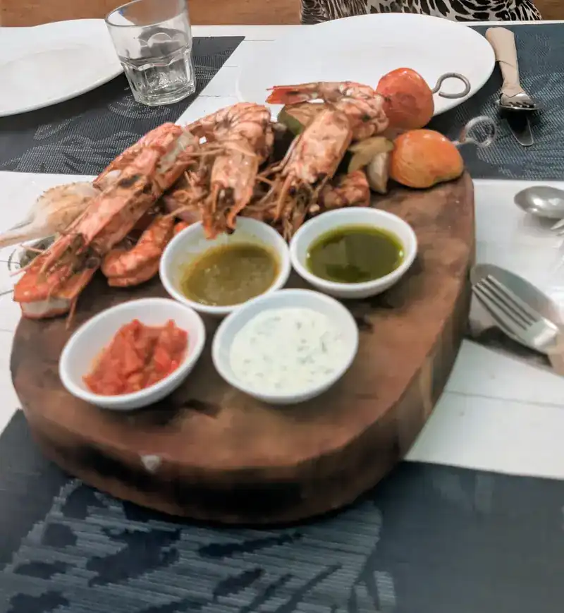 Grilled prawns on a wooden board with four dipping sauces