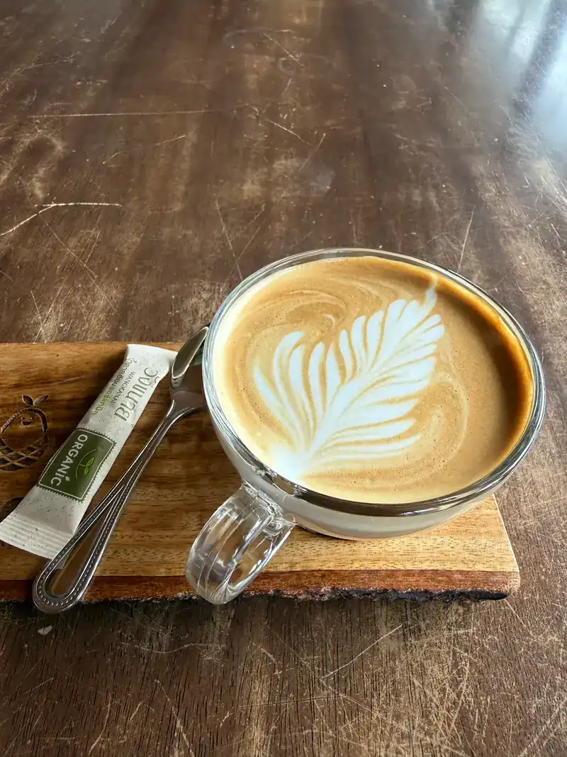 A latte with leaf art on a timber board