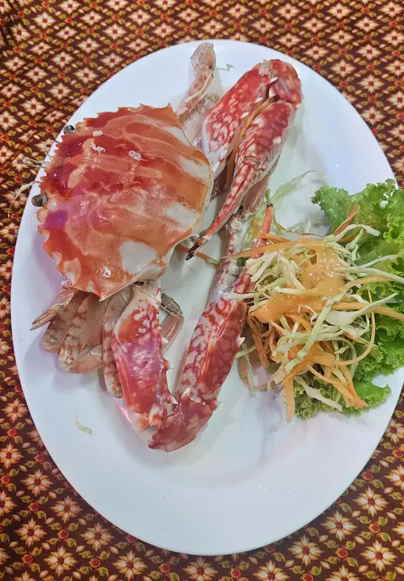 A whole cooked blue swimmer crab with salad on a white plate