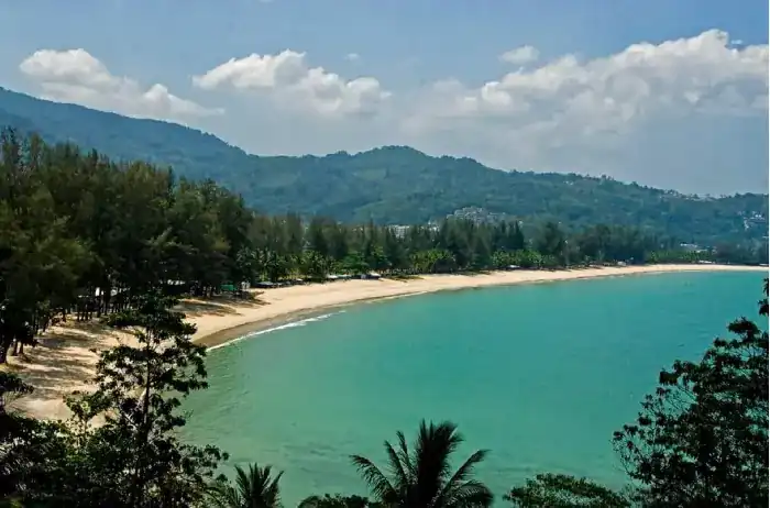 Kamala Beach seen from the hillside: a curve of sand, green water and forested hills