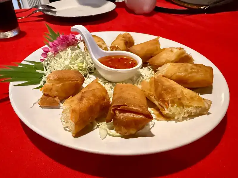 Fried spring rolls with sweet chilli sauce on shredded cabbage