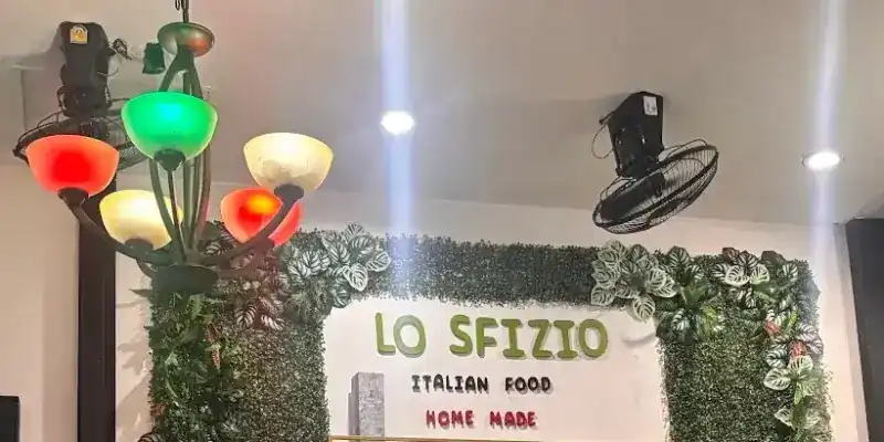 The green wall inside Lo Sfizio with its sign, Italian food, home made, under coloured glass lamps