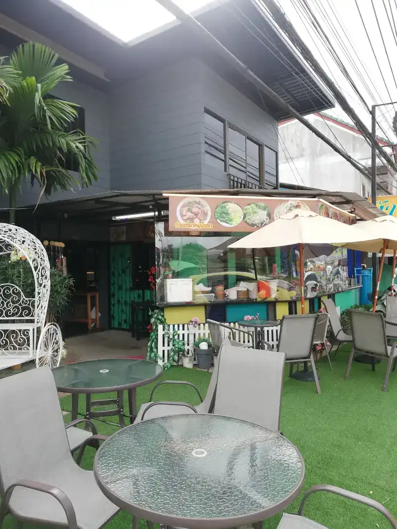 Garden tables on green turf beside the white iron carriage seat, by day
