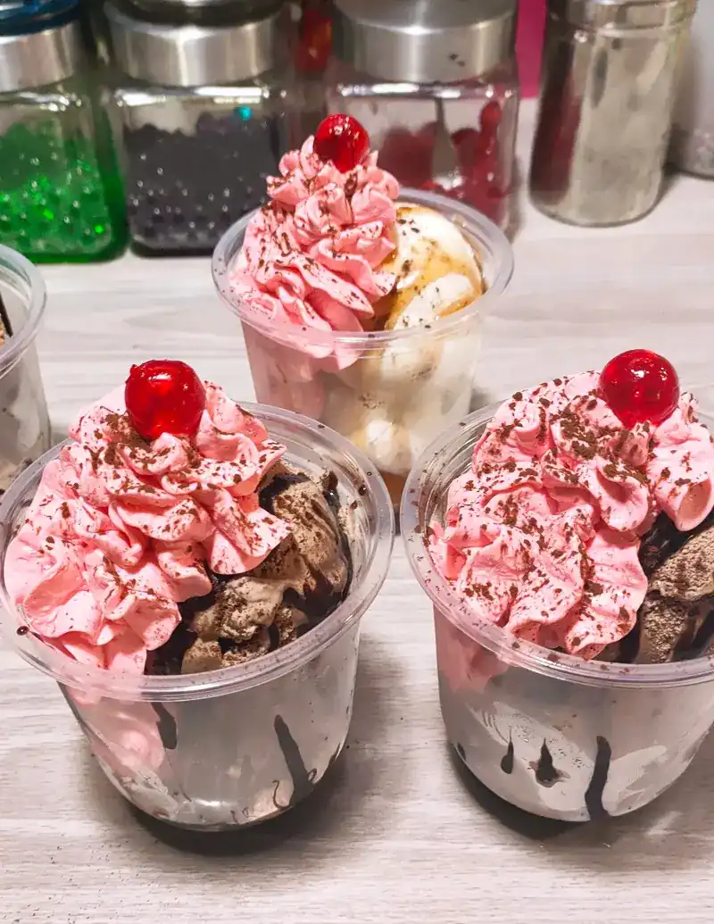 Ice-cream cups with pink cream and a cherry on top