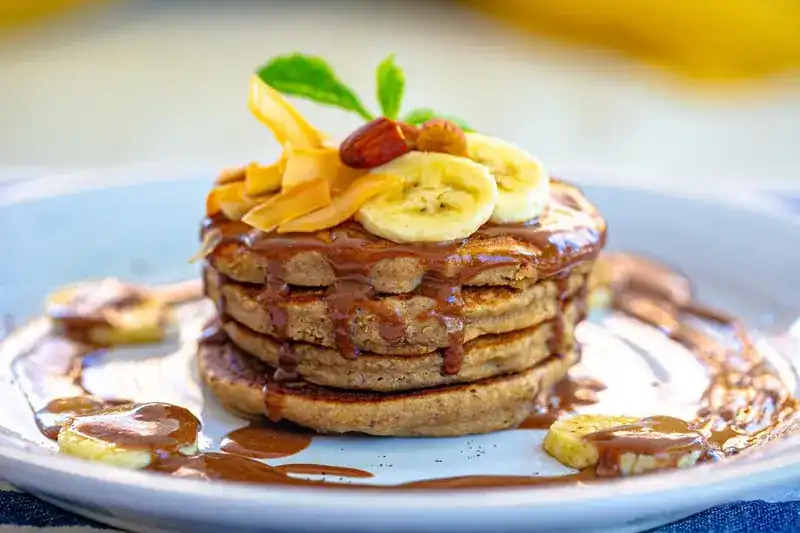 A stack of pancakes with banana slices and sauce