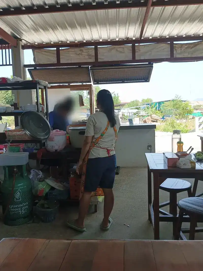 The cooking station under the tin roof, with rice pots and a gas bottle