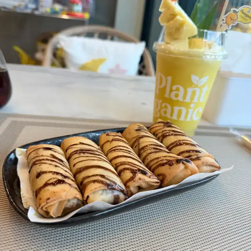 Rolled pastries drizzled with chocolate, and a yellow smoothie topped with pineapple
