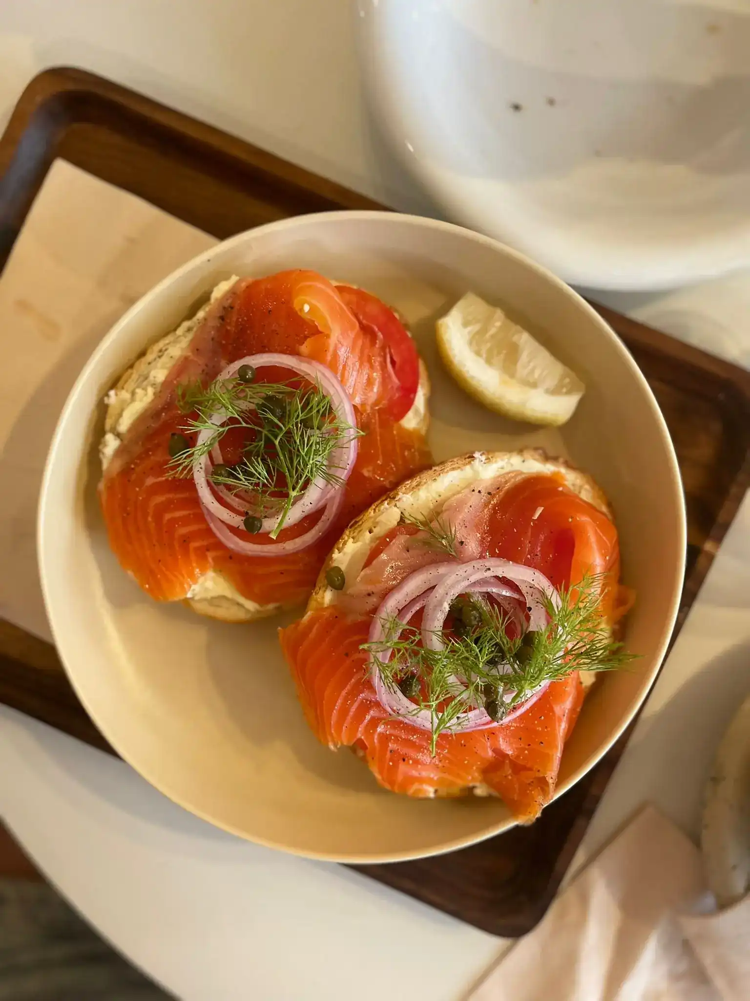 Smoked salmon bagel with cream cheese, red onion, capers and dill, served open with a wedge of lemon