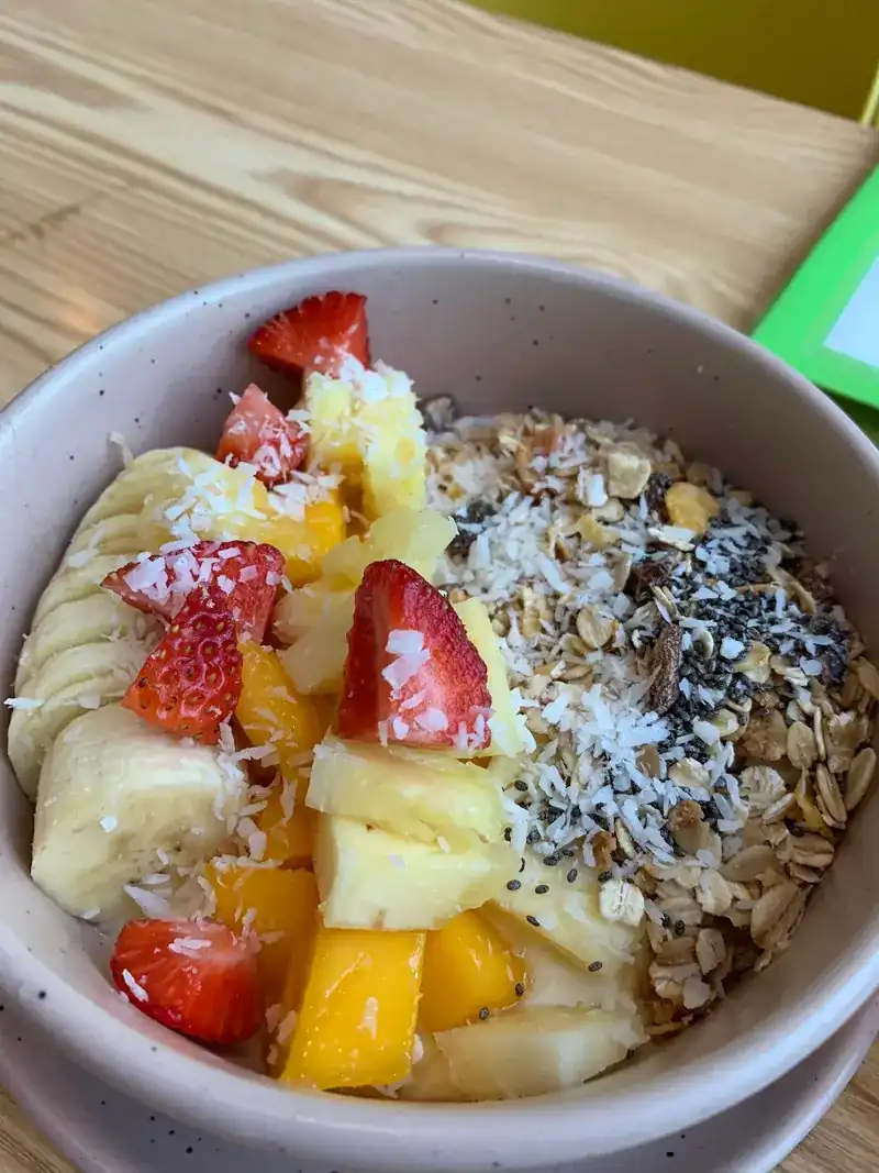 A bowl of granola, coconut, chia, strawberries, banana, pineapple and mango
