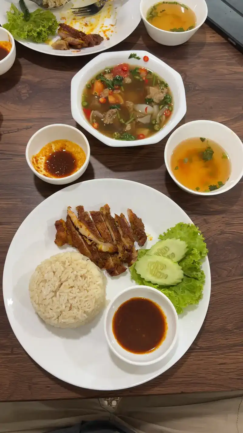 A guest's table seen from above: rice with sliced chicken, dipping sauces and bowls of soup