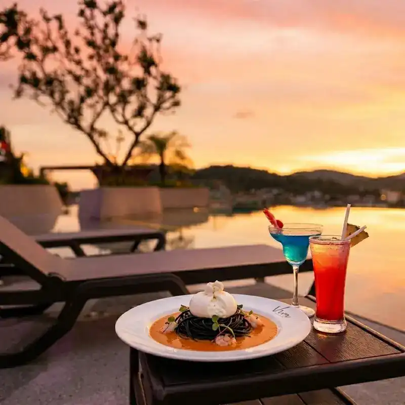 Squid-ink spaghetti with burrata on a table by the pool at sunset