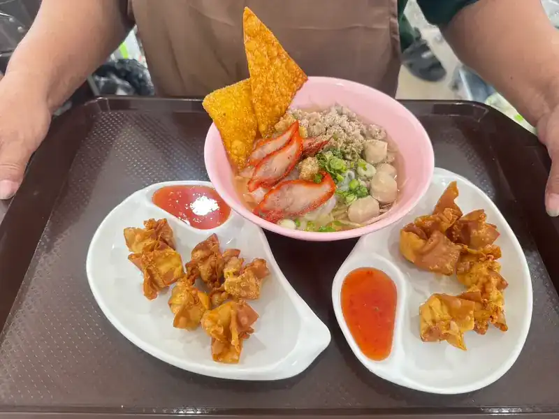 Clear noodle soup with red pork and meatballs, with two plates of fried wontons