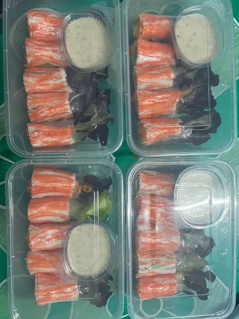 Four takeaway boxes of crab sticks with salad leaves and a cup of creamy dressing