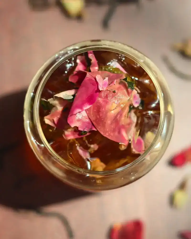 A glass of tea with rose petals, seen from above