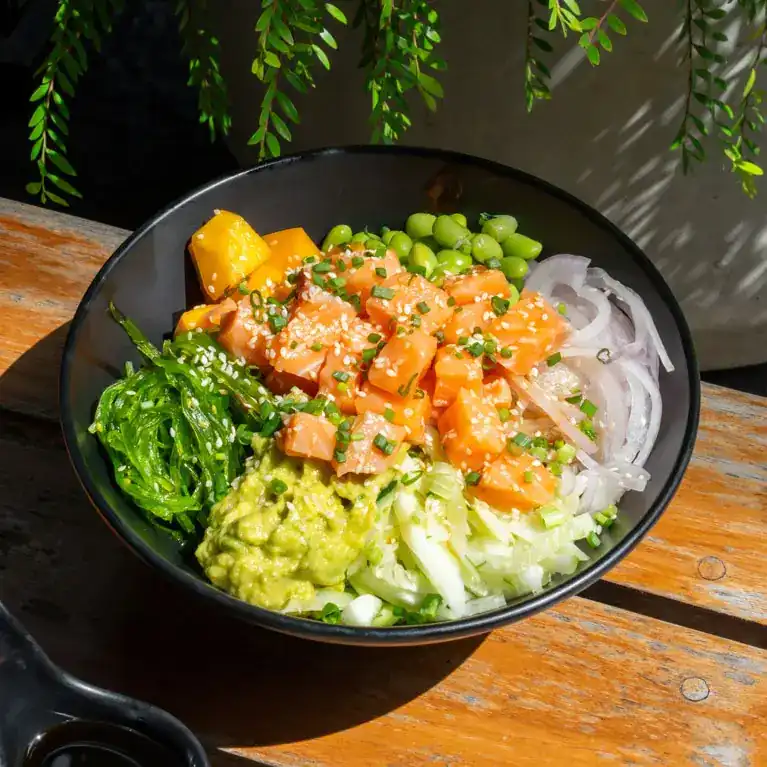 Bowl of diced salmon with mango, edamame, seaweed salad and avocado