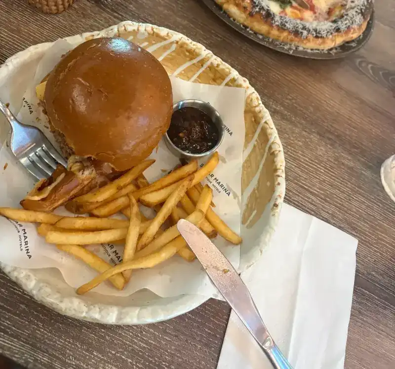 Burger with fries and a dip on a paper-lined plate