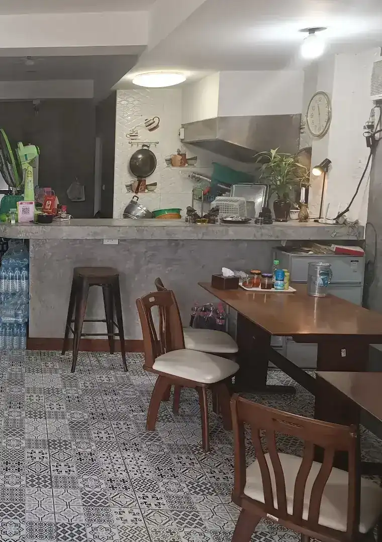Inside the shop: wooden chairs, a bar stool, a concrete counter and black-and-white patterned floor tiles