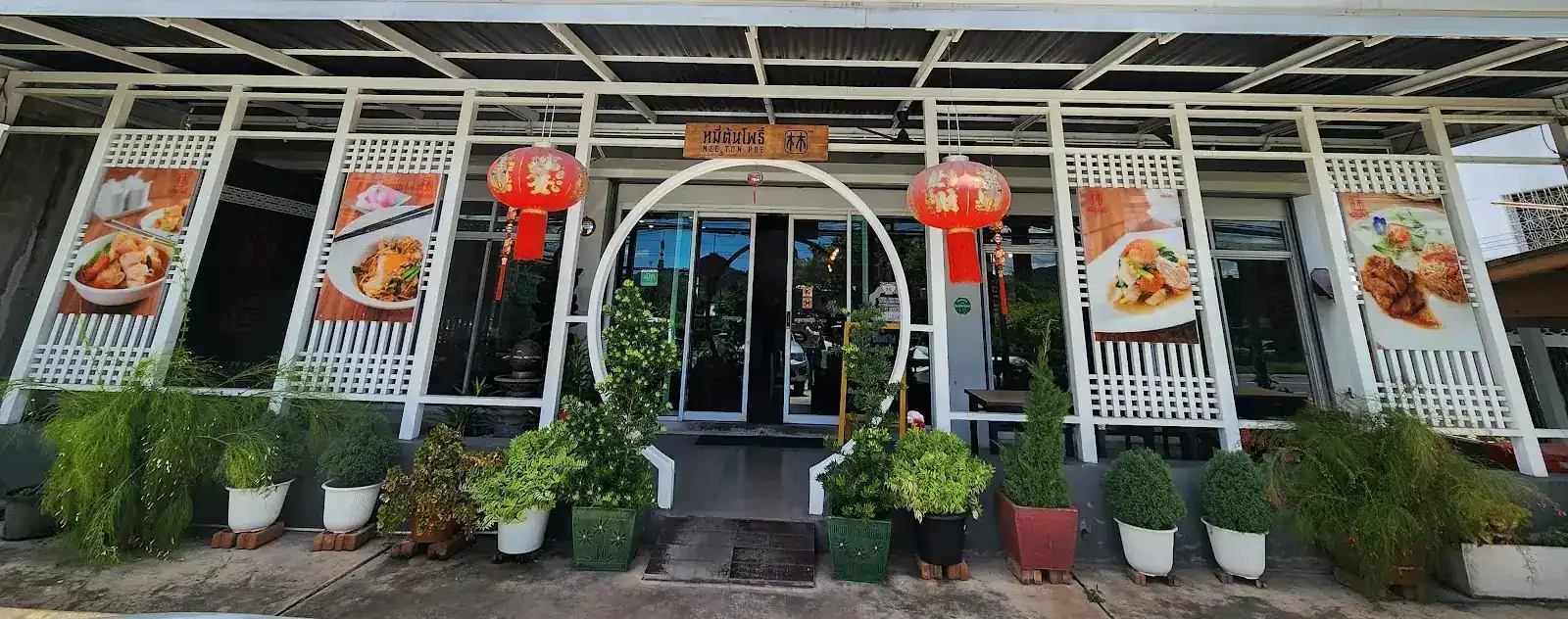 The Thalang shopfront: a white round doorway between two red lanterns, with potted plants along the front