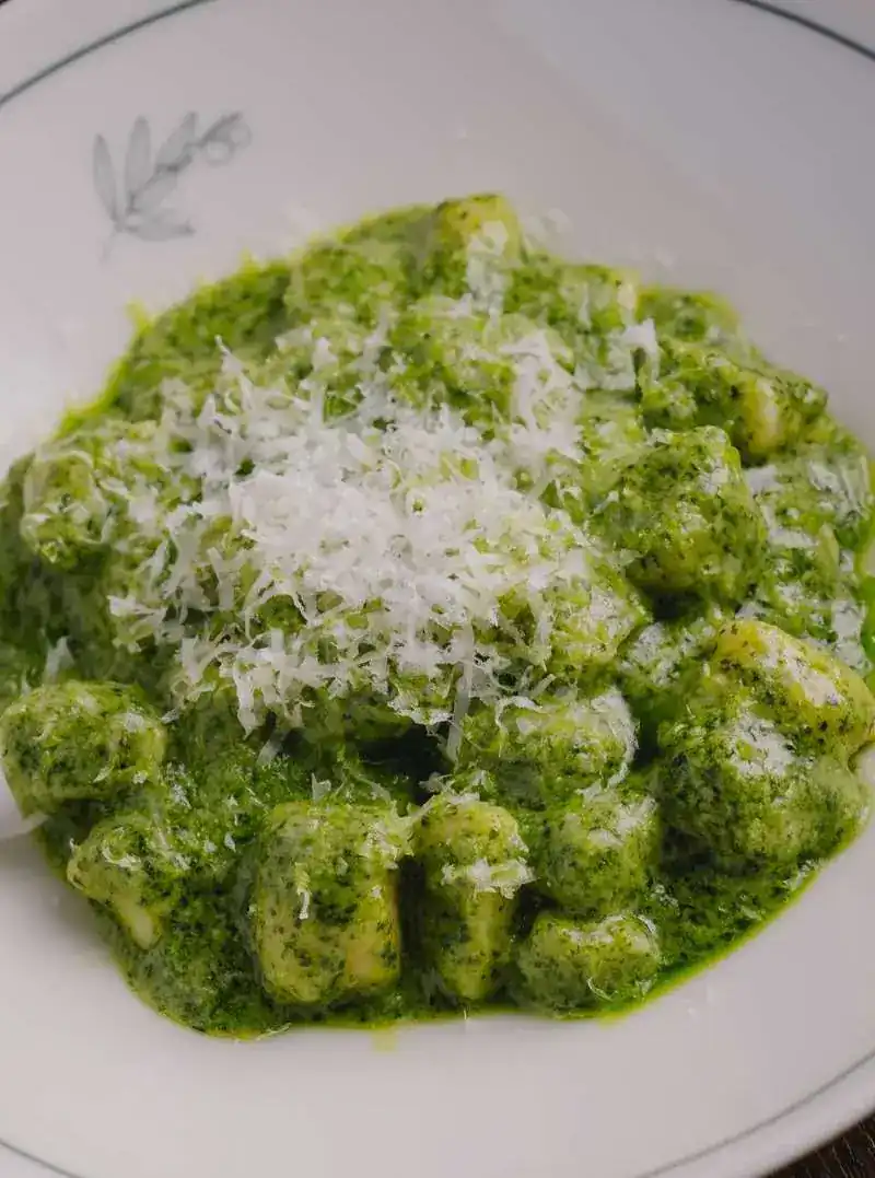 Gnocchi in green pesto under grated cheese
