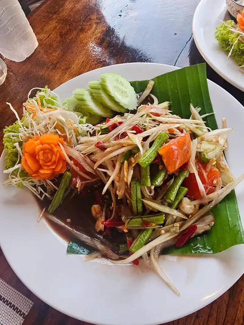 Papaya salad with long beans, tomato and cucumber on banana leaf